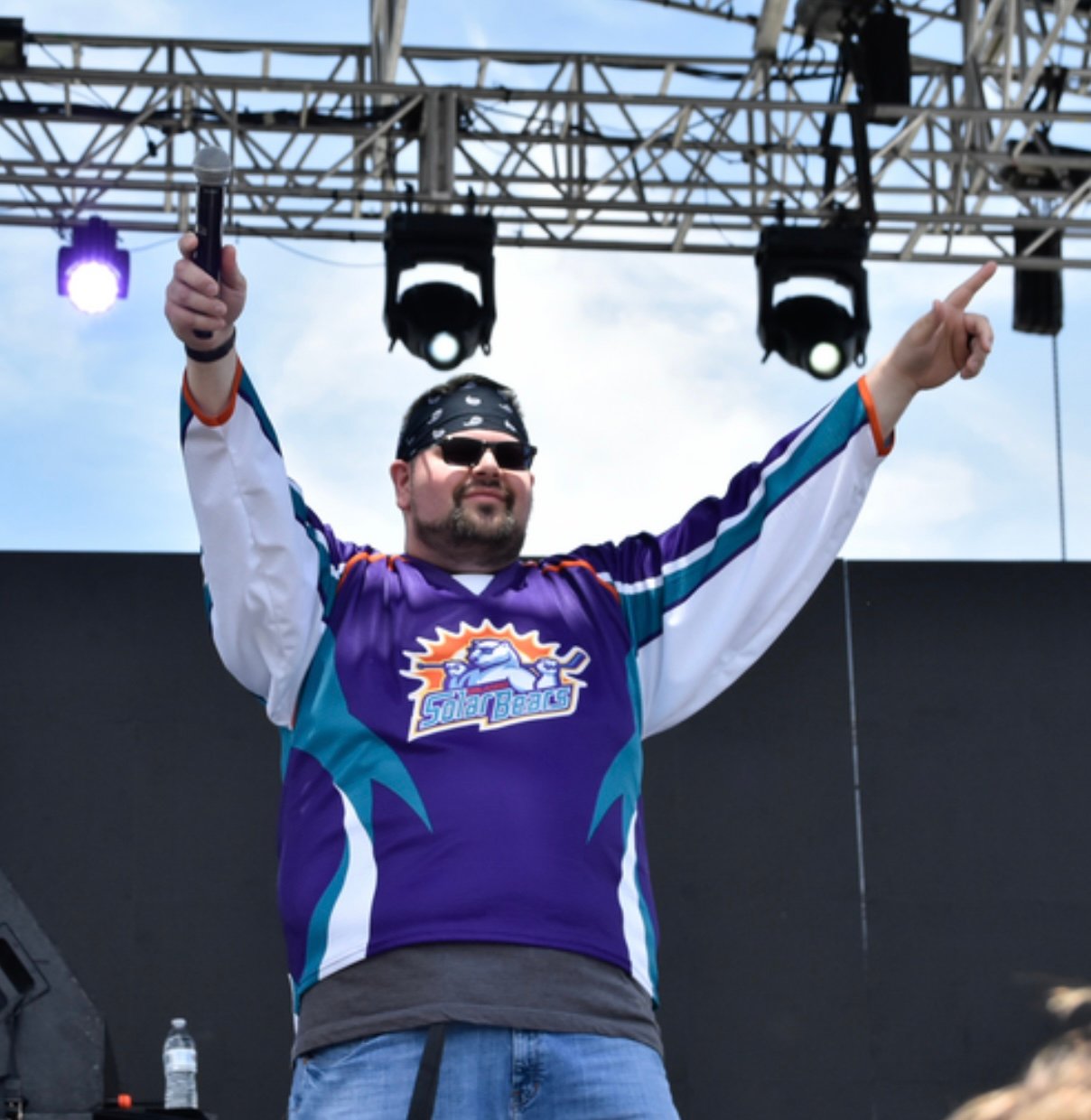 Bryan on stage with arms raised at Earthday Birthday